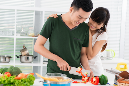 happy pregnant couple preparing dinner in the kitchen